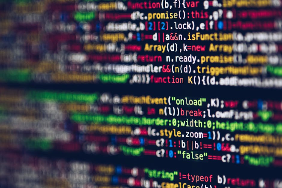 A close-up photograph of a computer screen displaying lines of colorful programming code in shades of red, blue, green, yellow, and white against a dark background. The code appears slightly blurred, 